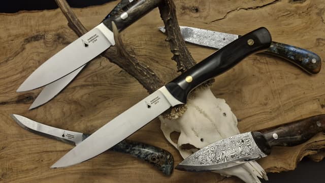 Fixed-blade knives arranged around a deer skull and antlers