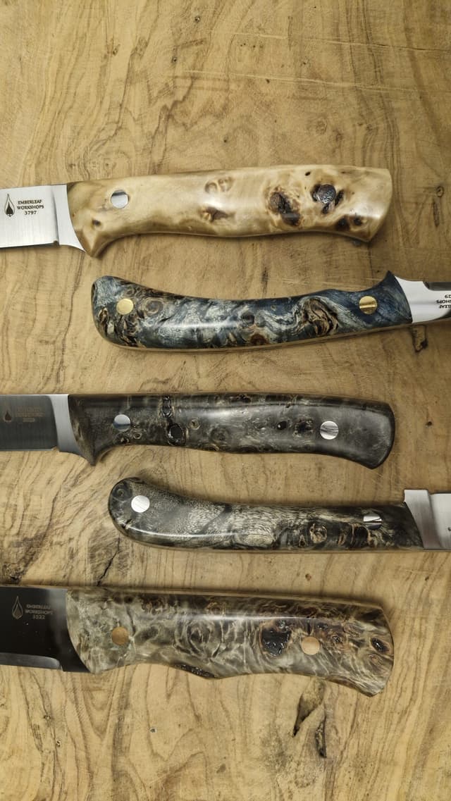 A row of knives with burl handles on the workbench