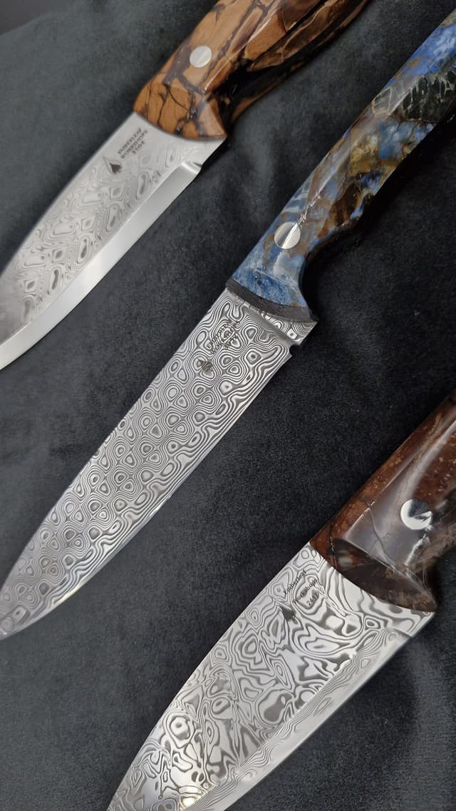Three Damascus knives with dark and burl handles