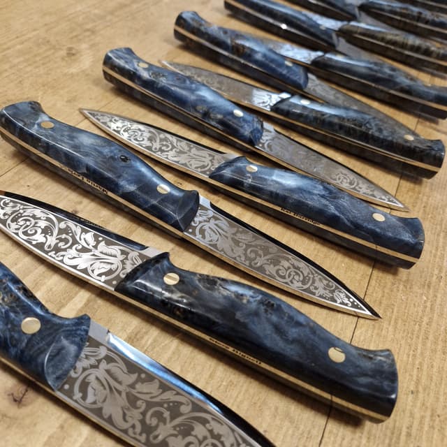 A commissioned batch of scroll-etched blades on the bench