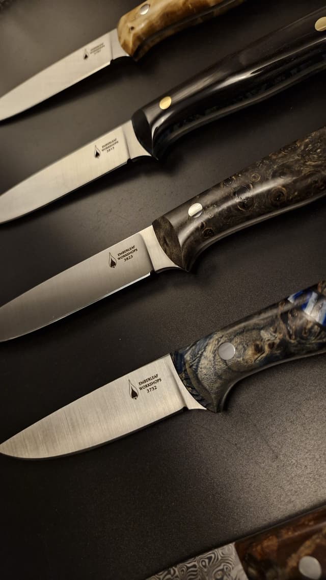 Satin-finished blades with dark and burl handles laid in a row