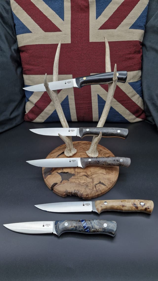 Five knives arranged in front of a Union flag cushion