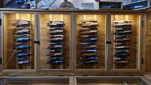 Four oak cabinets of knives resting in their leather sheaths