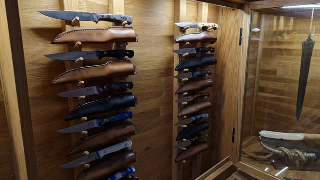 Sheathed knives racked inside the oak showroom cabinet