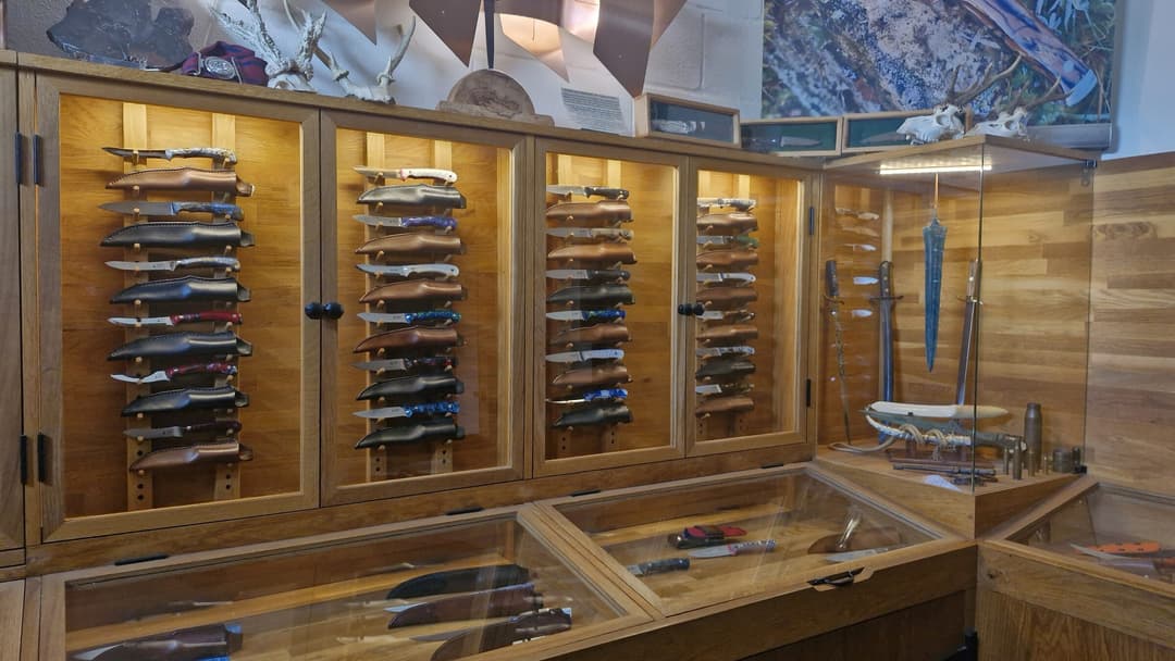 The showroom in Petworth: oak cabinets of knives on pegs, a glass counter, and a side case of older blades