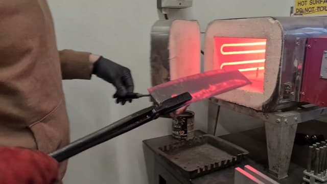 A blade lifted glowing from the heat-treat kiln