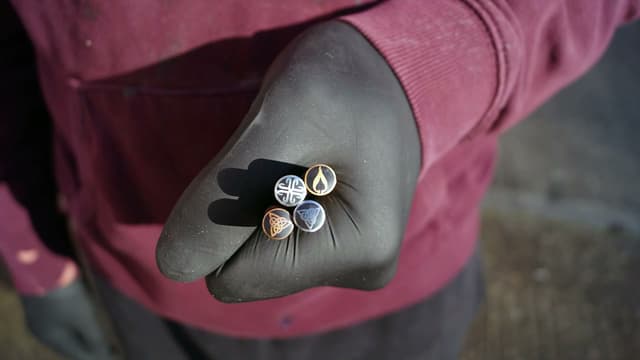 A gloved hand holding a few mosaic pins