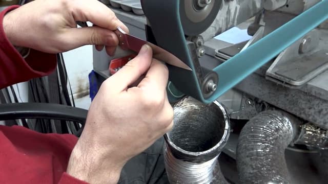 A blade checked against the belt grinder
