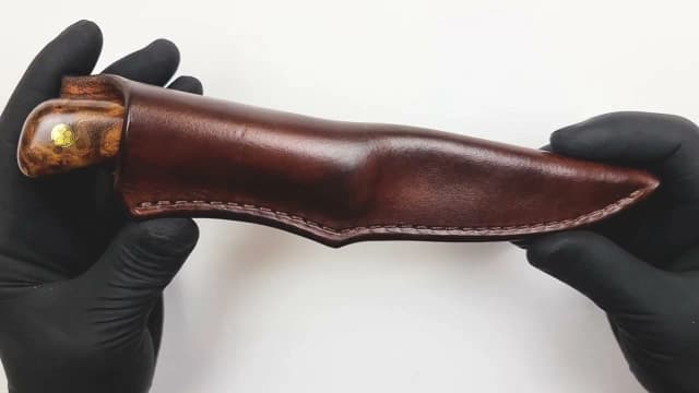 A finished Emberleaf knife slid into its hand-stitched leather sheath