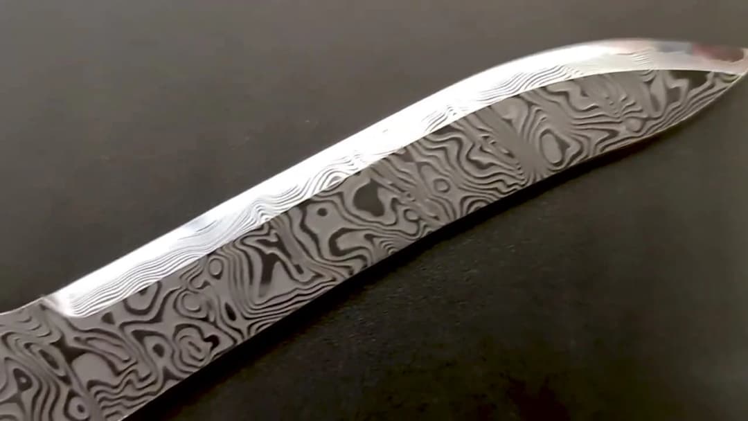 Close-up of an etched Damascus blade, dramatic flowing pattern in the steel
