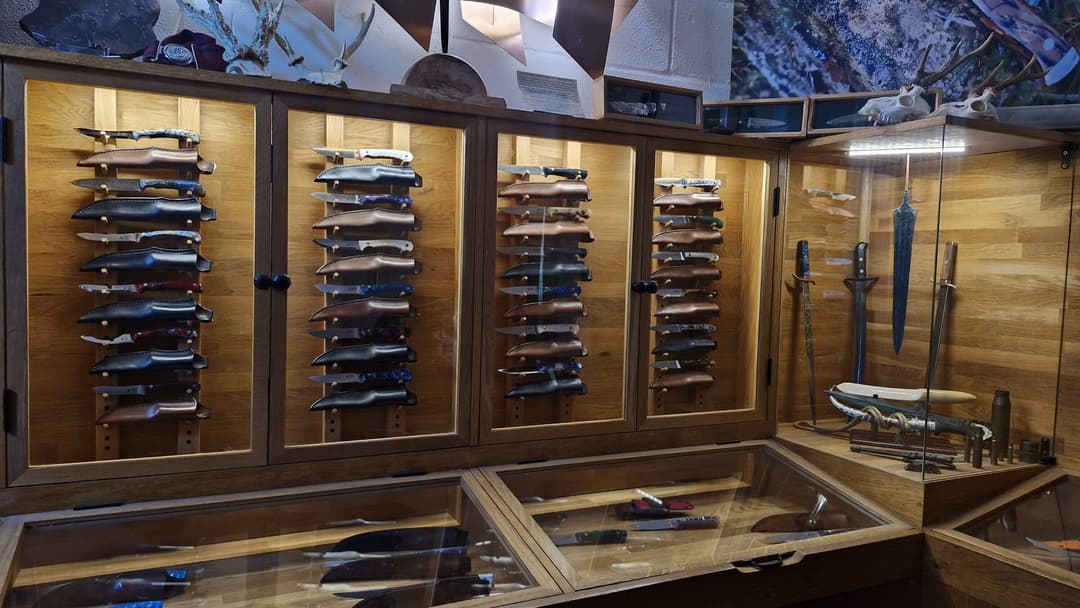 The Emberleaf showroom from the left — oak cabinets, a glass counter and a side case of daggers and antique blades