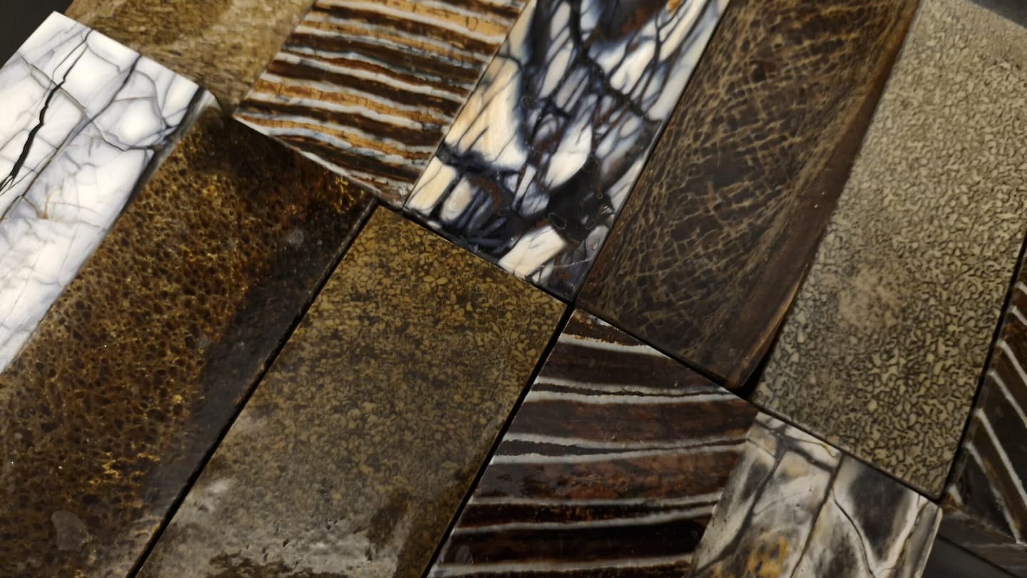 Handle blanks laid edge to edge — mammoth ivory, mammoth molar, spalted and stabilised burls, mineral composites